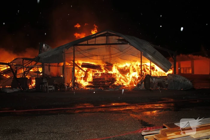 Brandweer bestrijdt grote uitslaande brand in twee loodsen