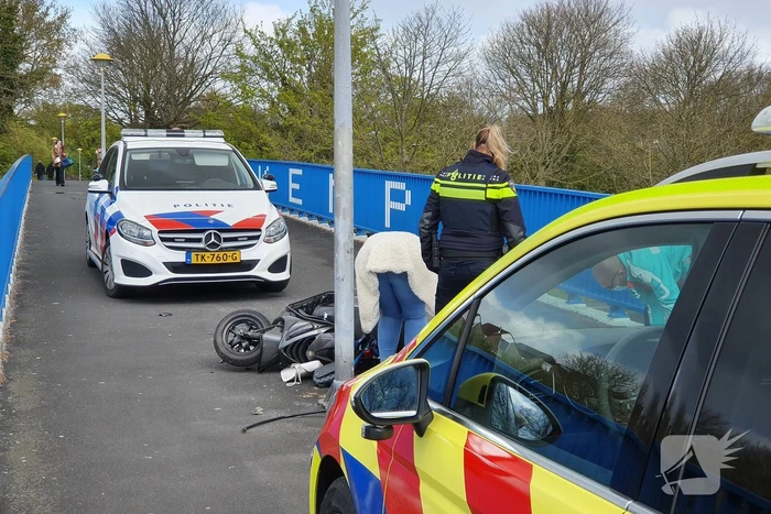 Man en vrouw gaan met scooter onderuit op fietsbrug