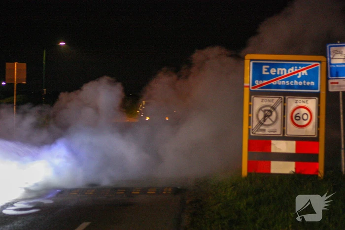 Brandweer blust brandende band op midden van weg