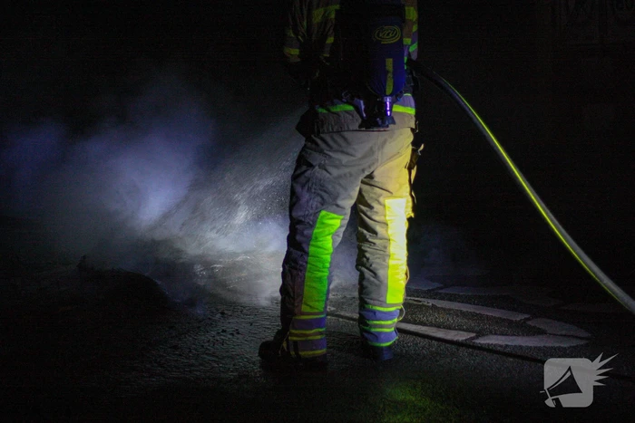 Brandweer blust brandende band op midden van weg