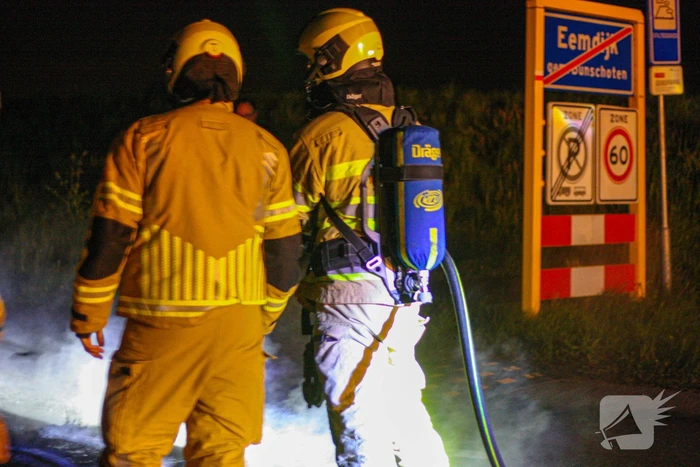 Brandweer blust brandende band op midden van weg