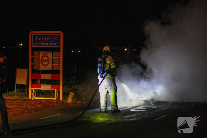 Brandweer blust brandende band op midden van weg
