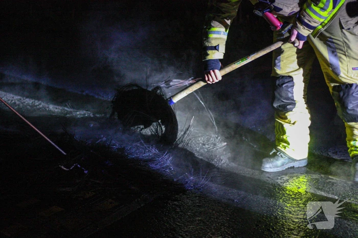 Brandweer blust brandende band op midden van weg