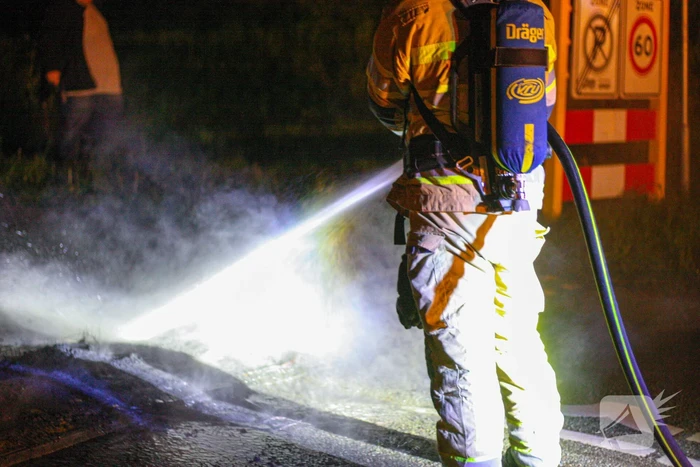 Brandweer blust brandende band op midden van weg