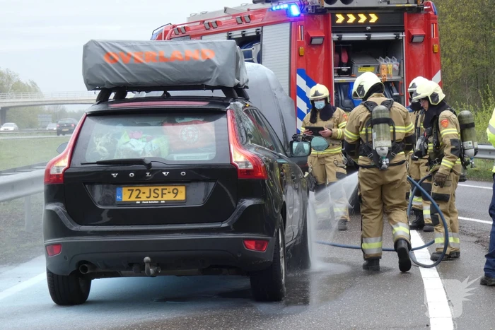 Brandweer blust brand in motorcompartiment van personenauto
