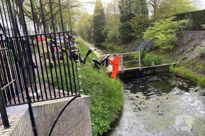 Persoon rijdt met scootmobiel het water in
