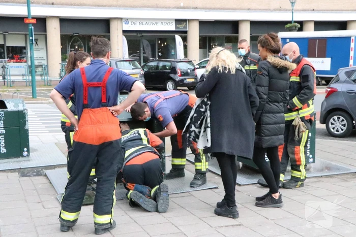 Brandweerman kruipt in ondergrondse papiercontainer voor verloren horloge