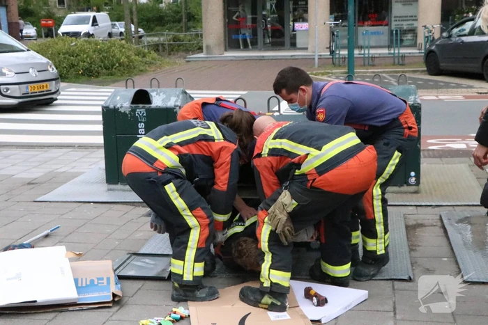 Brandweerman kruipt in ondergrondse papiercontainer voor verloren horloge
