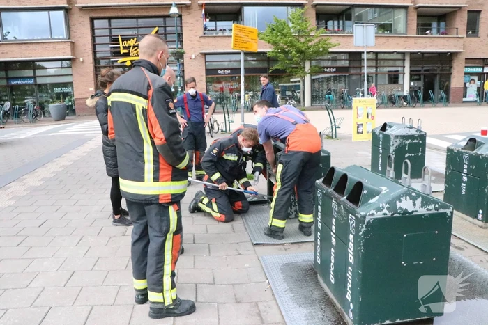 Brandweerman kruipt in ondergrondse papiercontainer voor verloren horloge