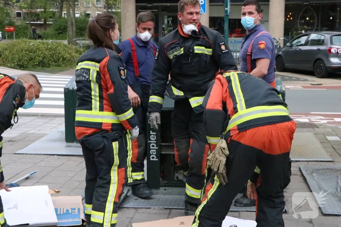 Brandweerman kruipt in ondergrondse papiercontainer voor verloren horloge