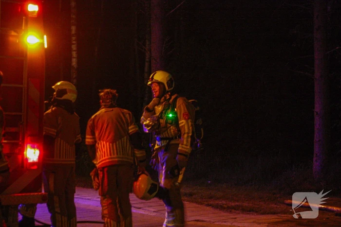 Brandweer blust brandende stukken hout