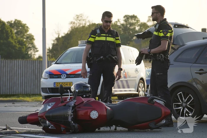 Personenauto en motor botsen op rotonde