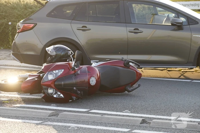 Personenauto en motor botsen op rotonde