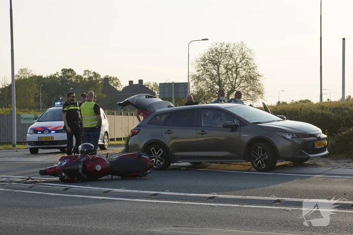 Personenauto en motor botsen op rotonde