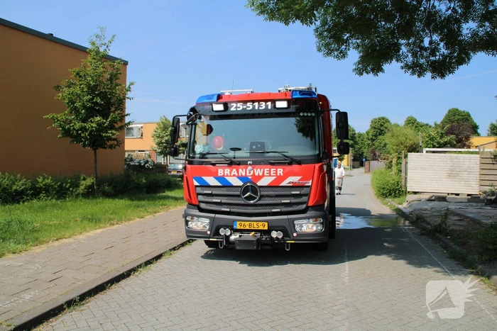Brandweer blust in brand staande schutting