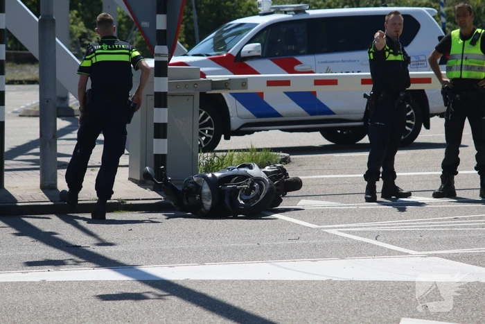 Auto botst op scooter voor ingang veerdienst
