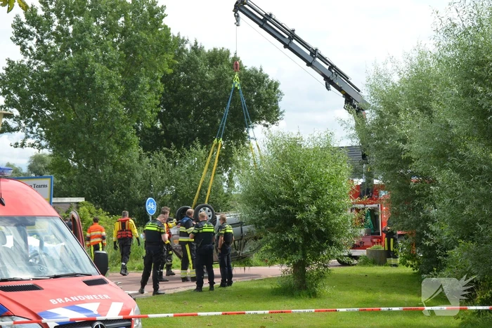 Auto schiet van de weg en belandt ondersteboven in het water