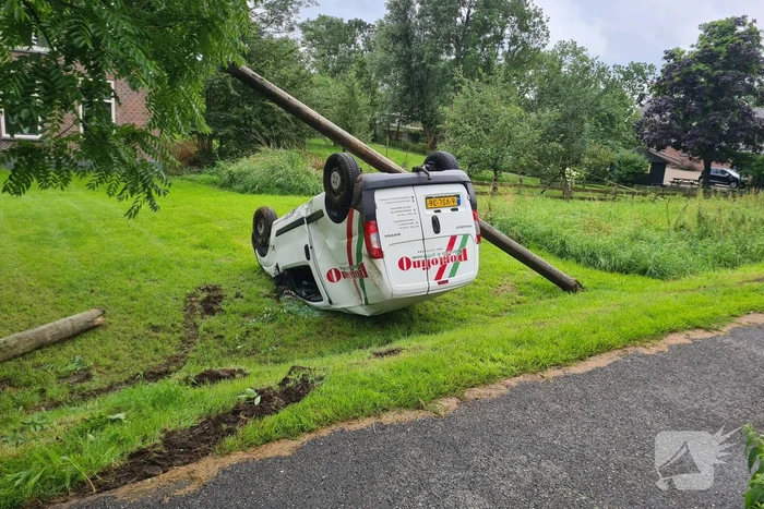 Bezorgauto slaat over de kop en ramt stroommast