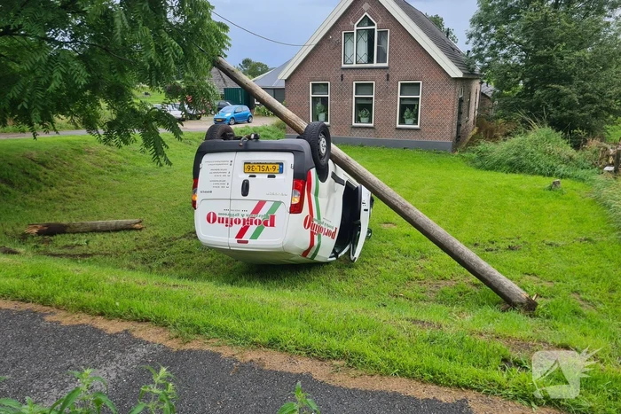Bezorgauto slaat over de kop en ramt stroommast