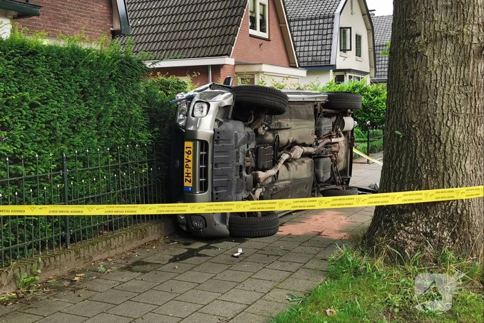 Auto belandt op zijn kant tegen hekwerk
