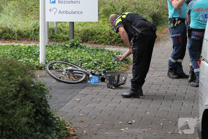 Vrouw met fiets gaat onderuit voor ingang ziekenhuis