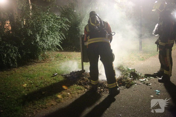 Brandweer blust brand bij prullenbak
