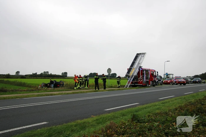 Auto raakt na botsing van de weg en belandt op de kop in weiland