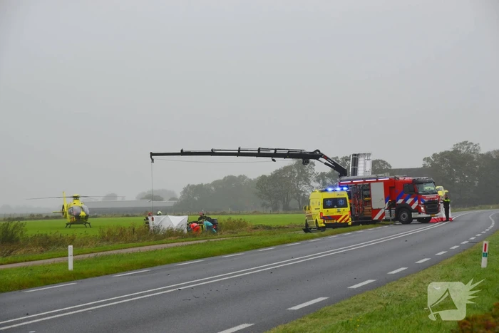 Auto raakt na botsing van de weg en belandt op de kop in weiland