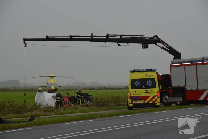 Auto raakt na botsing van de weg en belandt op de kop in weiland