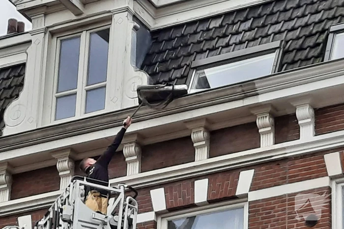 Brandweer haalt kussen uit dakgoot