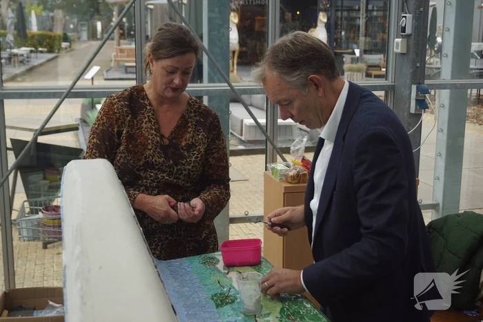 Burgemeester Röell helpt bij beplakken Social Sofa bij woonwarenhuis Nijhof