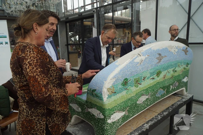 Burgemeester Röell helpt bij beplakken Social Sofa bij woonwarenhuis Nijhof