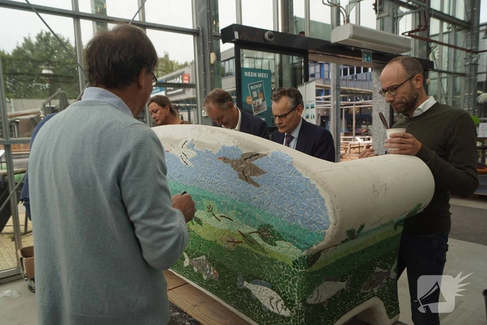 Burgemeester Röell helpt bij beplakken Social Sofa bij woonwarenhuis Nijhof