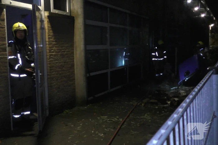Brandweer blust brandende container tegen school
