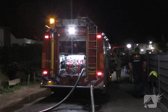 Brandweer blust brandende container tegen school