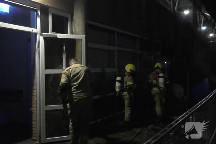 Brandweer blust brandende container tegen school