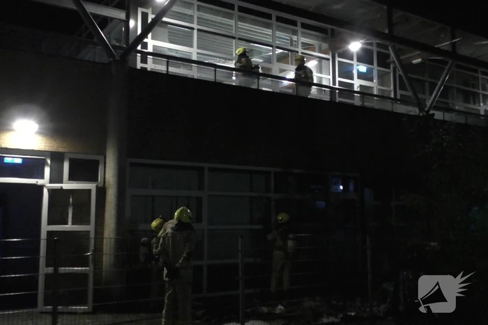 Brandweer blust brandende container tegen school