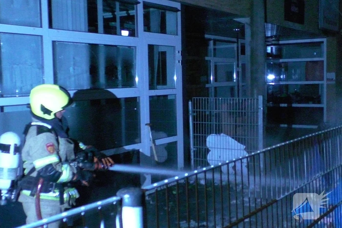 Brandweer blust brandende container tegen school