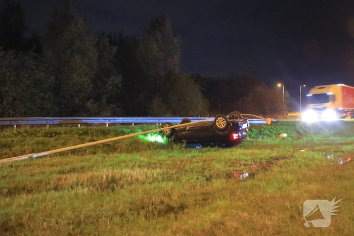 Auto belandt op z'n kop naast snelweg