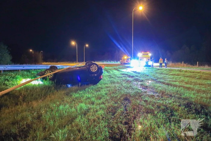 Auto belandt op z'n kop naast snelweg