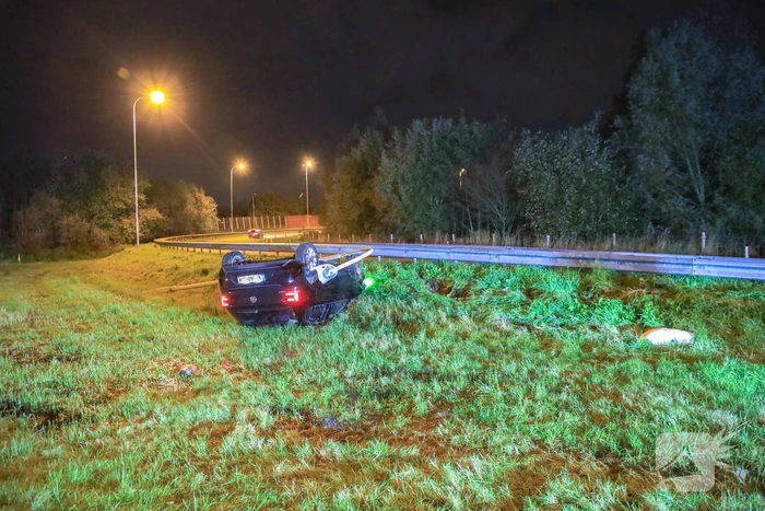 Auto belandt op z'n kop naast snelweg