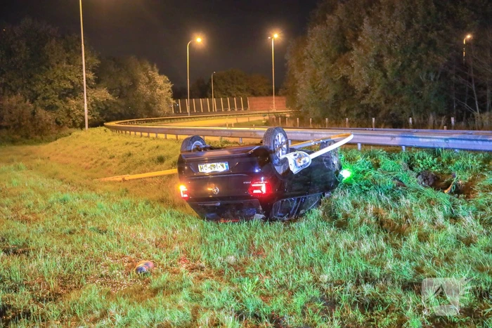 Auto belandt op z'n kop naast snelweg