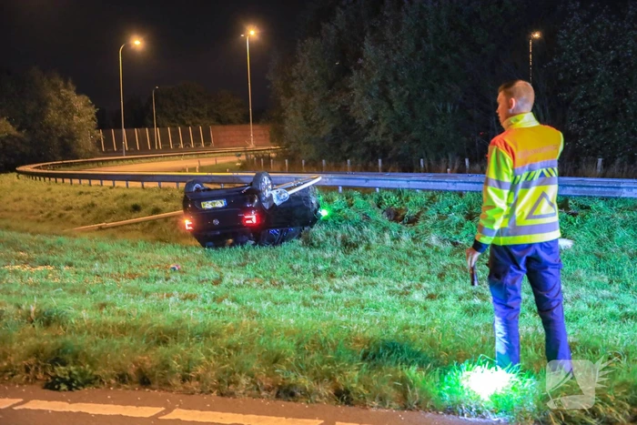 Auto belandt op z'n kop naast snelweg