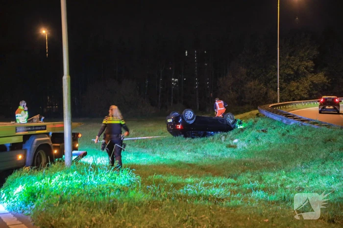 Auto belandt op z'n kop naast snelweg