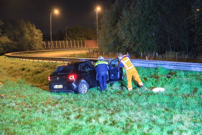Auto belandt op z'n kop naast snelweg