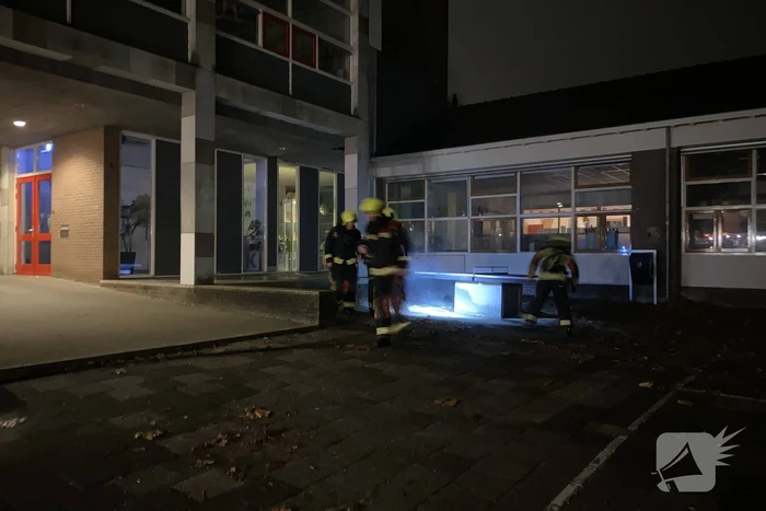 Brandweer blust brandende hoop kranten op schoolplein
