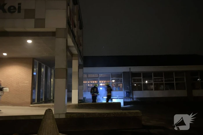 Brandweer blust brandende hoop kranten op schoolplein