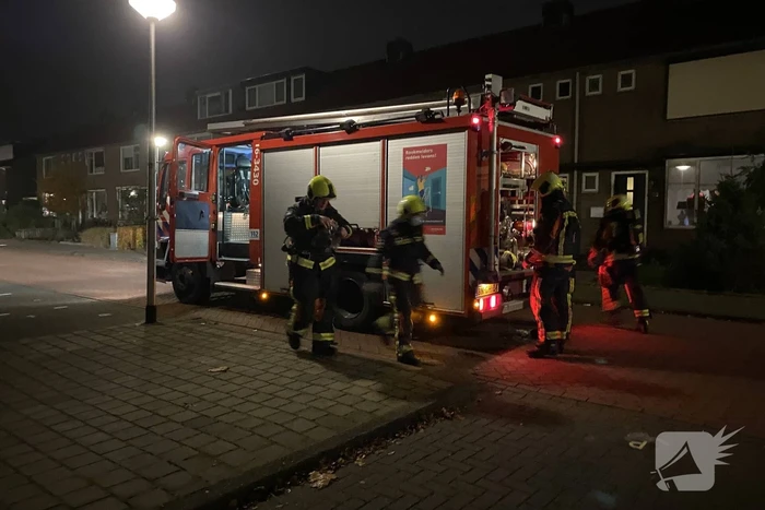 Brandweer blust brandende hoop kranten op schoolplein