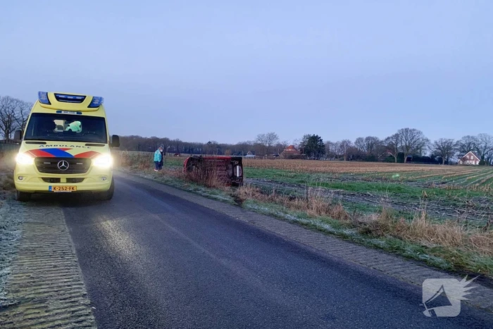Auto belandt op zijn kant langs spekgladde weg