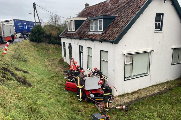 Auto rijdt van dijk en knalt tegen woning